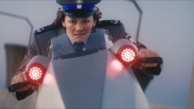 The cop — Close-up: a police officer on a hover bike, red lights flaring.